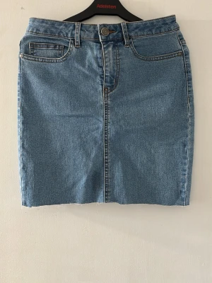 Otroligt snygg jeanskjol - Säljer en klassisk blå jeanskjol. Kjolen har fickor, bälteshällor och stängs med knapp och dragkedja framtill. Perfekt basic-plagg med bra och snygga kontrastsömmar. Denna kjol passar perfekt för den kommande sommaren, när man vill vara bekväm och snygg
