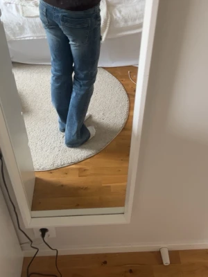 Blå slitna bootcut jeans - Ett par blå bootcut jeans med slitningar och hål på knäna. Storlek 170.