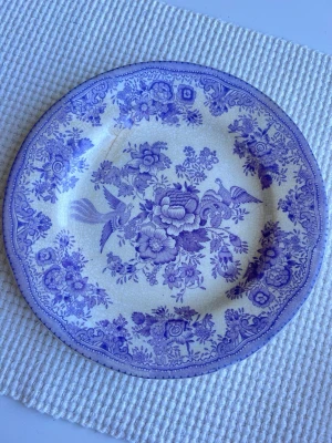 Gustavsberg Fasan Tallrik Asiatic Pheasants - En flat tallrik från Gustavsberg. Diameter 21cm. Krakelerad och ett brunt märke på ovansidan som syns även på undersidan. Lite blekare färg i verkligheten. En extremt liten skada i kanten (se näst sista bilden). Granska bilderna noga.