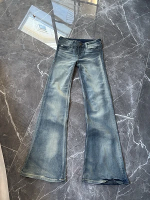 Blåa utsvängda jeans Cheap Monday - Säljer ett par blåa jeans från Cheap Monday med utsvängda ben och slitna detaljer. Jeansen har klassisk femficksmodell, låg midja och en stor vit logolapp bak med Cheap Monday-tryck och döskalle. Perfekta för dig som gillar retrostil och statement-plagg. Säljer dem för att dem tyvärr var för små men skit snygga 💓💓och är aldrig använda 💓💓💓