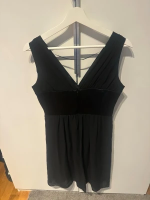 Svart cocktailklänning från Esprit - Snygg svart cocktailklänning från Esprit med v-ringad front och bred midja. Klänningen är ärmlös och har en kort längd, perfekt för dig som gillar stilrena och klassiska plagg. Materialet är mjukt och lätt polyester.