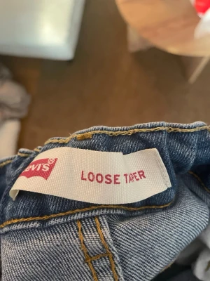 Levi's Loose Taper ljusblå jeans - Ljusblå jeans från Levi's med loose taper passform. Klassisk femficksdesign och snygga kontrastsömmar. Perfekt för dig som gillar en avslappnad och trendig look. Materialet är denim och jeansen har en modern, avsmalnande siluett.