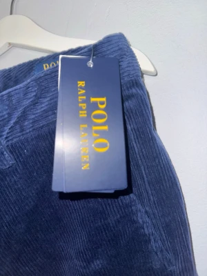 Blåa manchesterbyxor Polo Ralph Lauren - Snygga blåa manchesterbyxor från Polo Ralph Lauren med raka ben och klassisk passform. Byxorna har två bakfickor med knappar och är tillverkade i mjuk manchester för en trendig och bekväm look.