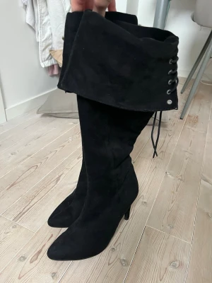 Svarta höga stövlar/boots - Snygga svarta stövlar i mockaimitation med hög klack. Stövlarna har snörning  upptill och dragkedja på insidan för enkel påtagning. Storlek 36 men passar mig med storlek 37