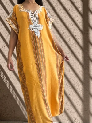 Gul randig marockansk  kaftanklänning med broderi  - Lång, loose-fit kaftanklänning i gul med smala ränder i orange och grönt. V-ringad hals med vit broderad detalj framtill och korta ärmar. Perfekt för varma dagar och har en avslappnad, bohemisk vibe.
