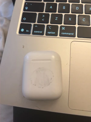 Vita trådlösa hörlurar i laddningsetui - Säljer AirPods, dem är i befintligt skick och eftersom det är en såpass gammal modell så säljer jag billigt även fast dem funkar perfekt. Säljer eftersom jag köpt nya! Absolut lägsta jag kan gå för är 200 och då behövs en diskussion isåfall