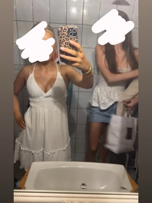 Vit sommarklänning med volang - Söt vit klänninh med smala axelremmar och djup v-ringning. Klänningen har volangdetaljer nertill och är perfekt för varma dagar. Lätt och luftig modell som ger en avslappnad känsla.