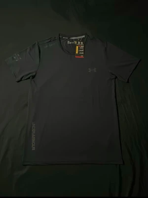 Svart reflective (rainbow) t-shirt från Under Armour - Cool svart t-shirt från Under Armour med reflekterande logga och text på bröstet och sidan. Materialet är lätt och snabbtorkande, perfekt för träning eller sport. T-shirten har rund hals och korta ärmar, och är designad för att ge bra rörelsefrihet.