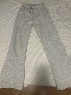 Grå mjukisbyxor från Gina Tricot - Säljer ett par ljusgrå mjukisbyxor från Gina Tricot, basically basics-kollektionen. Byxorna har raka ben, resår i midjan med dragsko och är tillverkade i mjukt sweatshirtmaterial. Perfekta för chill dagar hemma eller när du vill vara extra bekväm.