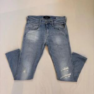 Ljusblåa Replay anbass jeans med feta slitningar  - Säljer ett par ljusblåa replay anbass jeans med snygga slitningar från fabrik | Storlek: 29/32 | Jeansen är uppsydda till 97cm långa | Hör av er vid minsta fråga!