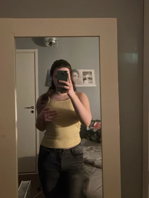 Ljusgul ribbad linnetopp - Säljer en ljusgul ribbad linnetopp från Monki med smala axelband och croppad passform. Perfekt för varma dagar och enkel att matcha med jeans eller shorts. Materialet är mjukt och stretchigt, vilket gör den bekväm att bära.