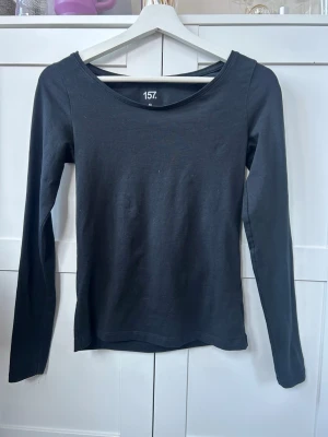 Svart långärmad topp från 157 - En enkel och stilren svart långärmad topp från  lager 157. Toppen går neråt på framsidan, så den är inte helt täckande vid halsen. 