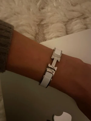 Vitt H-armband - Snyggt vitt armband med den ikoniska H-detaljen i silverfärgad metall. Armbandet har en stilren och modern design.