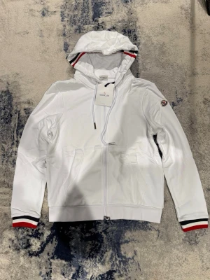 Vit Moncler zip hoodie - Säljer denna super feta Moncler zip Hoodien, ny med tags kvar. Nfc Scan funkar. Han på bild är 185cm, 75kg. Inget kvitto finns! Pris kan diskuteras vid snabb affär!