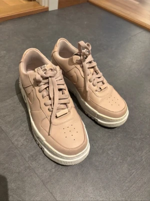 Rosa Nike Air Force - Köpta för längesedan på zalando, använda men inte överdrivet mycket, Stl 38 passar 37 fint också Dem är lite mer rosa irl men ljuset är väldigt gult så det ser annorlunda ut på bild