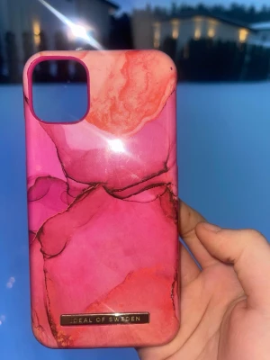Rosa marmorerat mobilskal iDeal of Sweden iPhone 11 - Snyggt mobilskal från iDeal of Sweden i ett rosa marmorerat mönster med inslag av orange och svart. Skalet är gjort i hårdplast och har en glansig finish. Perfekt för dig som vill ha ett unikt och färgstarkt skydd till mobilen. 