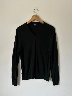 Mörkgrön V-ringad stickad tröja Uniqlo - Klassisk mörkgrön stickad tröja från Uniqlo med V-ringning och långa ärmar. Tröjan har en enkel och stilren design med ribbade muddar vid ärmslut och nederkant. Perfekt basplagg i garderoben och lätt att matcha till olika outfits. 8B12