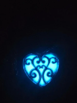 Halsband med självlysande hjärthänge i rostfritt stål  - Unikt halsband med ett hjärtformat hänge i silverfärgad metall och dekorativa snirkliga detaljer. Hänget lyser i blått i mörker och har en kedja i rostfritt stål. Perfekt accessoar för dig som gillar magiska och iögonfallande smycken.