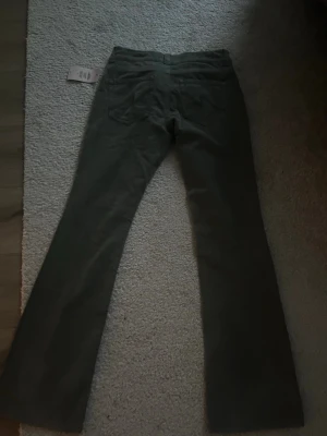Mörkgröna bootcut jeans från Nelly - Helt helt nya snygga mörkgröna jeans från Nelly med prislapp med bootcut passform och klassiska fem fickor. Jeansen har normal midja och stängs med dragkedja och två knappar. Perfekta för dig som vill ha en avslappnad men trendig look.