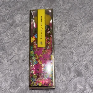 Heavenly Flowers parfym Victoria's Secret - Heavenly Flowers Eau de Parfum från Victoria's Secret i en färgglad glasflaska med blommigt mönster och gul kork. Flaskan rymmer 75 ml och har en elegant design med inslag av rosa, gult, blått och grönt. Perfekt för dig som gillar fräscha och blommiga dofter.
