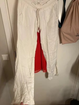 Vita linnebyxor från Roxy - Säljer ett par vita linnebyxor från Roxy med avslappnad passform och dragsko i midjan. Byxorna har två stora fickor framtill och ett litet broderat logomärke. Perfekta för en chill och stilren look.