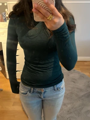 Mörkgrön långärmad topp - Snygg mörkgrön långärmad topp med tight passform. Tillverkad i mjukt och stretchigt material som sitter skönt mot kroppen. Perfekt att styla med jeans eller kjol för en clean look.