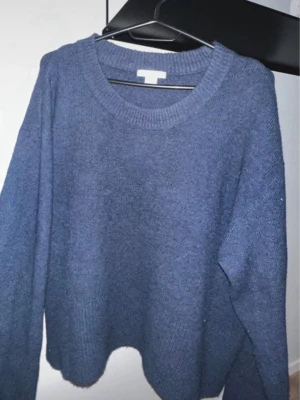 Mörkblå stickad tröja - Mysig mörkblå stickad tröja med rund halsringning och långa ärmar. Tröjan har en avslappnad passform och ribbstickade detaljer vid hals, ärmslut och nederkant. Perfekt för kyliga dagar och enkel att matcha med olika outfits.storlek 170 så som s