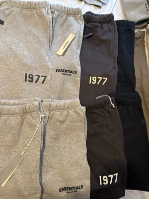 Essentials Fear of God shorts - Säljer flera par shorts från Essentials Fear of God med trycket '1977' på benet. Finns i färgerna grå, svart och mörkgrå. Shorts har resår i midjan och sidofickor. Perfekta för en chill och avslappnad stil. Till sommaren skriv för intresse!