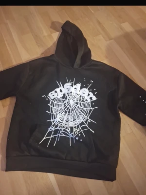 Sp5der hoodie - Säljer en svart hoodie med stor vit spindelnätsgrafik och texten 'spider' på bröstet. Hoodien har huva och magficka framtill. Perfekt för dig som gillar streetwear och vill sticka ut med en unik design.