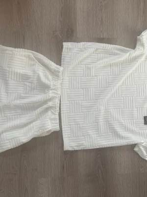 Vitt quiltat set med t-shirt och shorts - Säljer ett vitt quiltat set med t-shirt och shorts. Setet har ett rutigt mönster i strukturen och är gjort i ett mjukt, stretchigt material. Perfekt för en avslappnad och trendig look. Elastisk midja på shortsen för extra komfort. Tröjan är stor i Storleken 13-14Y funkar som en S