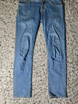 Jacob cohen jeans modell nick slim fit - Säljer ett par ljusblå jeans med smal passform och klassisk femficksdesign. Jeansen har normal midja och dragkedjegylf. Perfekta till en avslappnad stil och passar till det mesta i garderoben.