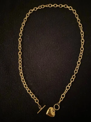 Guldigt halsband med hjärthänge gjort i rostfritt stål  - Snyggt halsband i guldfärgad metall med grova länkar och ett hjärtformat hänge. Halsbandet är gjort i rostfritt stål 🙌☀️