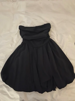 Svart axelbandslös kort klänning - Svart kort klänning med puffig kjol och draperad överdel från HM i storlek S💕