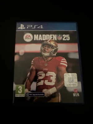 Madden NFL 25 till PS4 - Säljer spelet Madden NFL 25 till PlayStation 4. Omslaget har en spelare i röd och vit amerikansk fotbollströja från San Francisco 49ers. Spelet är i ett blått plastfodral och har åldersmärkning 3+. Perfekt för dig som gillar sportspel och NFL.