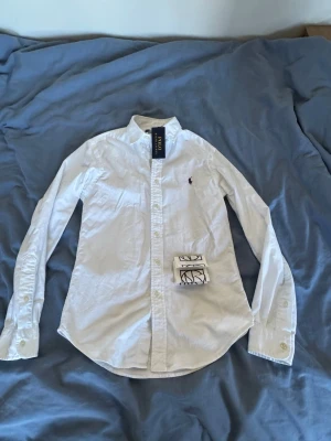 Vit skjorta från Polo Ralph Lauren - Klassisk vit skjorta från Polo Ralph Lauren, slim fit Oxford skjorta som passar perfekt nu till sommaren. Skjortan är helt ny och endast provad, Skjortan är köpt från NK i Göteborg , Skjortan bär storleken xs för herr. Den köptes för 1500kr. Obs kvitto finns! Hör av er vid frågor eller funderingar😊