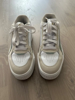 Beige och vita sneakers med mintdetaljer - Snygga sneakers i beige och vitt med mintgröna detaljer på sidan. Skorna har tjock sula, perforerad tå och klassisk snörning. Materialet är en mix av läderimitation och textil. Perfekta för dig som vill ha en fräsch och trendig look.