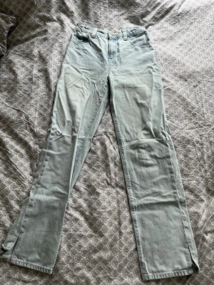 Ljusblå raka jeans Tommy Hilfiger - Säljer ett par ljusblå raka jeans från Tommy Hilfiger med klassisk femficksmodell och diskret logga på bakfickan. Jeansen har hög midja, bälteshällor och är tillverkade i denim. Perfekta för en avslappnad och trendig look.