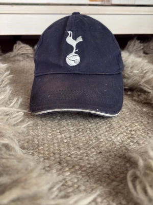 Tottenham hotspurs mörkblå keps från 2024 - En mörkblå keps jag säljer, den kan ändra storlek och är i bra skick.