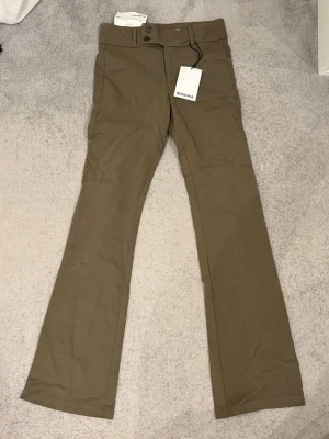 Gröna bootcut kostymbyxor  - Snygga gröna kostymbyxor från Bershka med utsvängda ben och hög midja. Byxorna har knapp- och dragkedjestängning fram samt en ficka med knapp bak. Helt nya med lappar kvar då de inte passade mig. De är i storlek EUR38, Aldrig använt! 