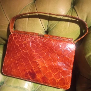 Handväska  - Riktigt fin retro väska i äkta reptilskinn! Ovanligt nog i helt perfekt skick, då den aldrig verkar ha använts, se fodret. Fick den för länge sen men det var aldrig min stil. 25cm lång, 16cm hög och botten är 8cm bred. Kan vara en dyrgrip! 350 kr (+frakt)