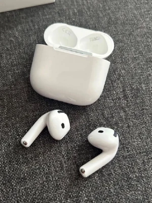 Trådlösa vita hörlurar med laddetui - Säljer ett par stilrena trådlösa hörlurar i blank vit plast med matchande laddningsetui. Hörlurarna har en smidig, ergonomisk design och passar perfekt för musik, poddar eller samtal på språng. Laddetui gör det enkelt att ta med och ladda hörlurarna var du än är.