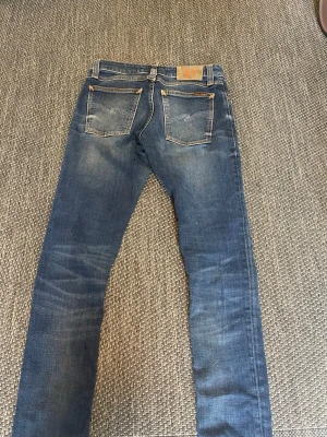 Blåa nudie jeans - * 👖 Nudie Jeans Co. * 📏 W28 L34 * 👖  Skinny Lin * 💙 Snygg blå tvätt med naturlig fade * ✂️ Råa, avklippta benslut * 🧡 Oranga detaljer * ✅ Bra begagnat skick, se bilder * 💰 Endast 299kr! * 💵 Priset kan diskuteras vid snabb affär * 🚚 Snabb frakt & svarar gärna på frågor