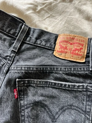 Svarta Levi's jeansshorts  - Snygga svarta jeansshorts från Levi's med rå kant och klassiska bakfickor. Shortsen är tillverkade i slitstark bomull. Perfekta för en avslappnad och trendig look.