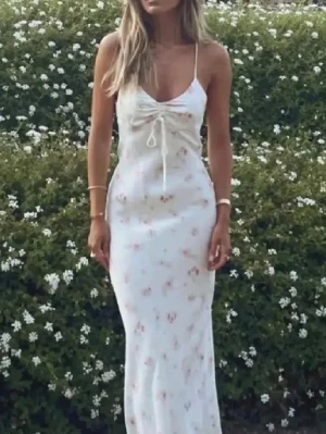 Vit långklänning med blommigt mönster - Säljer en vit långklänning med tunna axelband och blommigt mönster. Klänningen har snörning framtill vid bysten.
