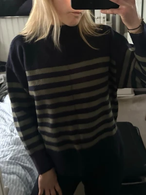 Randig stickad tröja från Zara - Mysig stickad tröja från Zara i mörkblått med breda olivgröna ränder. Skulle säga lite liten i storlek så passform perfekt för xxs-xs om man vill att den ska vara lite oversize (större), annars lite kortare för mig t.ex som har S🙌💖Har en lite fläck som ej synns.