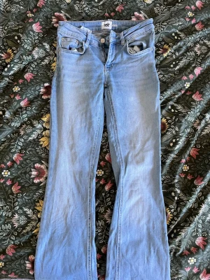 Ljusblå bootcut jeans med slitna benslut - Säljer ett par ljusblå bootcut jeans som inte längre kommer till någon användning, tecken på användning längst ner på byxorna men inget som man tänker mycket på!🙃💘 passar mig som bär 34/36!