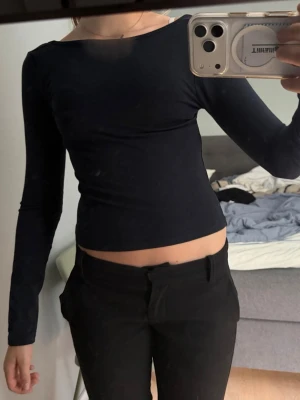 Svart croppad långärmad topp - Snygg svart croppad topp med långa ärmar och tight passform. Toppen har en enkel, stilren design och är perfekt att matcha med höga byxor eller kjol. Materialet känns mjukt och stretchigt, vilket gör den bekväm att bära hela dagen.