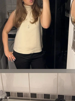Beige topp-Zara - Säljer en beige stickad topp med hög polokrage och ärmlös design. Från Zara i strl S/36. Använd fåtal gånger!