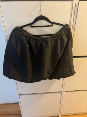 Svart puffig kortkjol - Säljer en svart puffig kortkjol med resår i midjan. Kjolen har en ballongliknande form och är tillverkad i ett slätt material som ger volym. Perfekt för dig som vill ha en statement piece i garderoben. Ny utan prislapp endast testad!