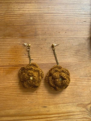 Bruna virkade blomörhängen - Mina handgjorda örhängen.  Bruna virkade blommor och guldig metallkedja.  Nickelfria!  Följ min Instagram för mer <3 @veras.smycken   Unika handgjorda örhängen i brun virkad design formade som blommor. Hängande modell med guldfärgade kedjor och små pärlor i mitten av varje blomma. Perfekta för dig som vill sticka ut med ett kreativt och bohemiskt smycke.
